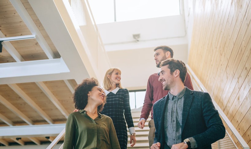 Four people walking downstairs talking to each other